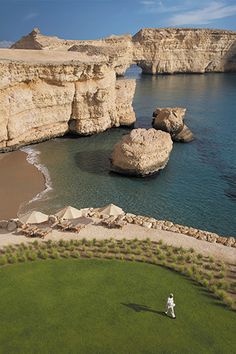 an aerial view of the ocean and cliffs near a beach with a person walking on it