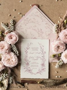 the wedding stationery is surrounded by flowers, feathers and an envelope with writing on it