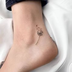 a small dandelion tattoo on the side of a woman's foot is shown