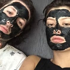 two people with black facial masks on their faces laying next to each other and looking at the camera