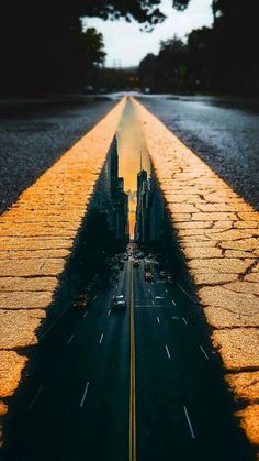 an empty road with cars driving down it and the sun reflecting in the street's shadow