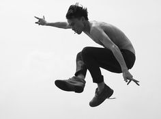 a man flying through the air while riding on top of a skateboard in front of a white sky