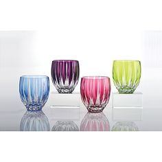 four different colored glass vases sitting on top of a white countertop next to each other