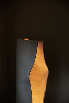 a lamp that is sitting on top of a wooden table next to a black wall