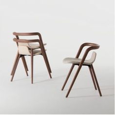 two wooden chairs with white upholstered seats and arms, one on the other side