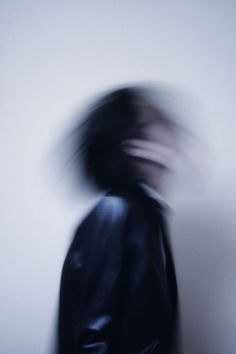 a blurry photo of a person in a black jacket with their head turned to the side