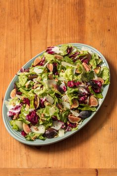 a salad with nuts and lettuce in a bowl on top of a wooden table