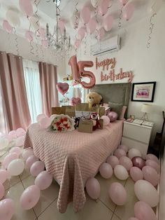 a room filled with pink balloons and teddy bears on top of a table surrounded by white flooring