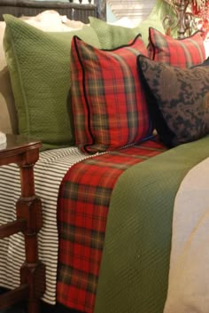 a bed with plaid sheets and pillows on top of it, in a room decorated for christmas