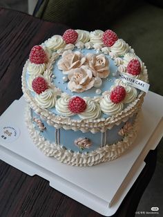 a blue and white cake with raspberries on top