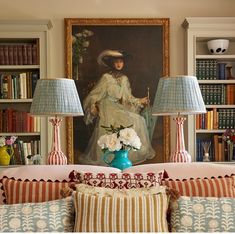 a living room filled with lots of furniture next to a painting on the wall and two lamps