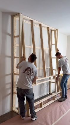 two men working on an unfinished wall in a room that is being built into the floor