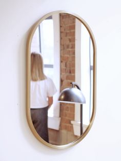 a woman standing in front of a mirror looking at her hair dryer on the wall