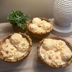 three wooden bowls filled with food sitting on top of a table next to a potted plant