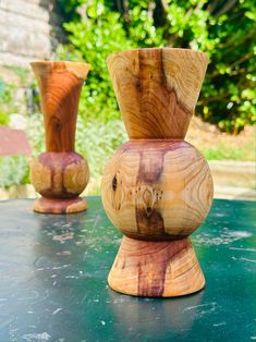 two wooden vases sitting on top of a green table next to eachother