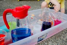 a toddler playing in a plastic container filled with liquid