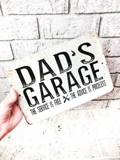 a person holding up a sign that says dad's garage