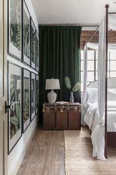 a bedroom with a canopy bed and pictures on the wall next to an open trunk