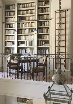 the room has many bookshelves and tables with chairs on them in front of an iron railing