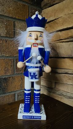 a blue and white nutcracker standing on top of a wooden table next to a brick wall