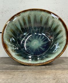 a green and brown bowl sitting on top of a wooden table