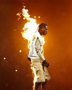 a man with dreadlocks standing in front of a fire