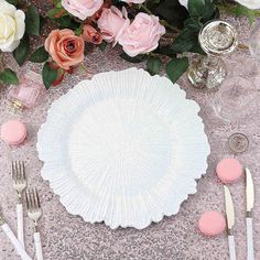 the table is set with pink and white flowers, silverware, and napkins