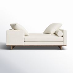 a white couch with two pillows on it's back and the rest of its arm