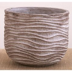 a close up of a vase on a table with a brown cloth underneath it and a white wall in the background