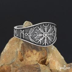 a silver ring with snowflakes on it sitting on top of a pile of rocks