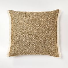 a gold and white pillow on a white wall