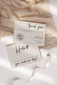 two thank you notes are on top of a white sheet with a ribbon around it