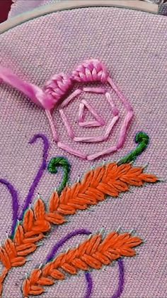 a close up of a embroidery on a piece of cloth with an orange and purple flower