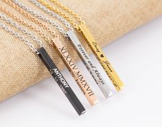 three personalized bar necklaces sitting on top of a cushioned pillow, one is gold and the other is silver