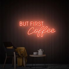 a neon sign that reads, but first coffee on the wall next to a table