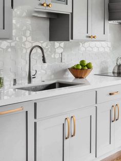 a bowl of green apples sitting on top of a kitchen counter next to a sink