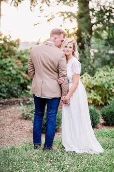 a bride and groom standing together in the grass