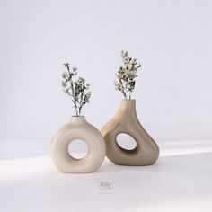 two vases with flowers in them on a white surface