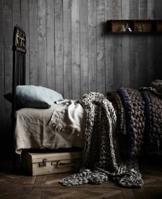 a bed sitting next to a window in a room with wooden walls and flooring