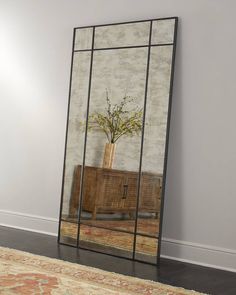 a large mirror with a vase on top of it next to a dresser and rug