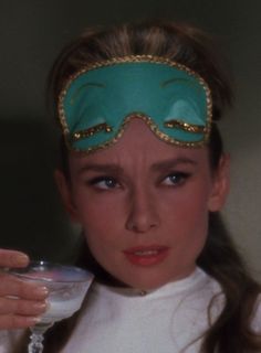 a woman wearing a mask and holding a drink