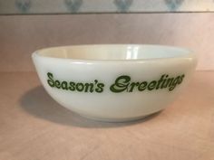 a white bowl with the words season's greetings written in green on it