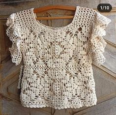 a white crocheted top hanging on a wooden door with the number 1 in front of it