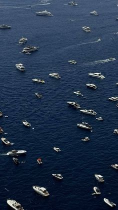 a large group of boats floating in the ocean next to each other on blue water