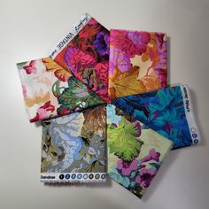 four different colors of fabric on top of each other, one with leaves and the other with flowers