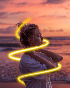 a woman standing on top of a beach next to the ocean with neon lights in her hair