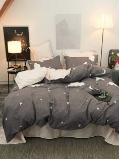 a bed with grey and white stars on it in a room next to two lamps