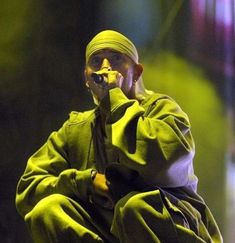 a man sitting on top of a stage while wearing a green jacket and bandana