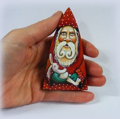 a hand holding a small wooden santa clause ornament