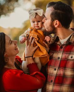 a man and woman are holding a baby in their arms as they smile into each other's eyes